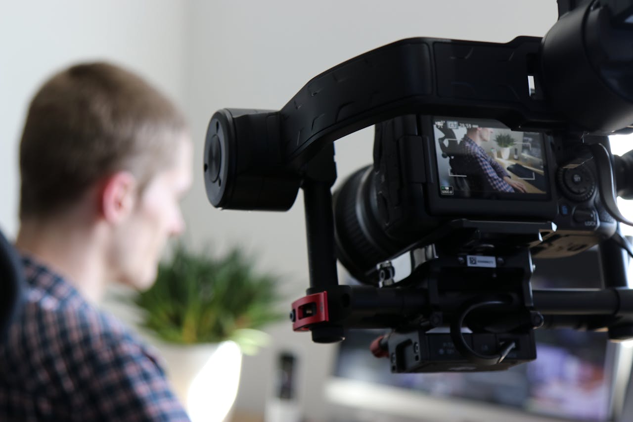 services-04 Close-up of camera filming a man in an indoor setting, highlighting professional video production